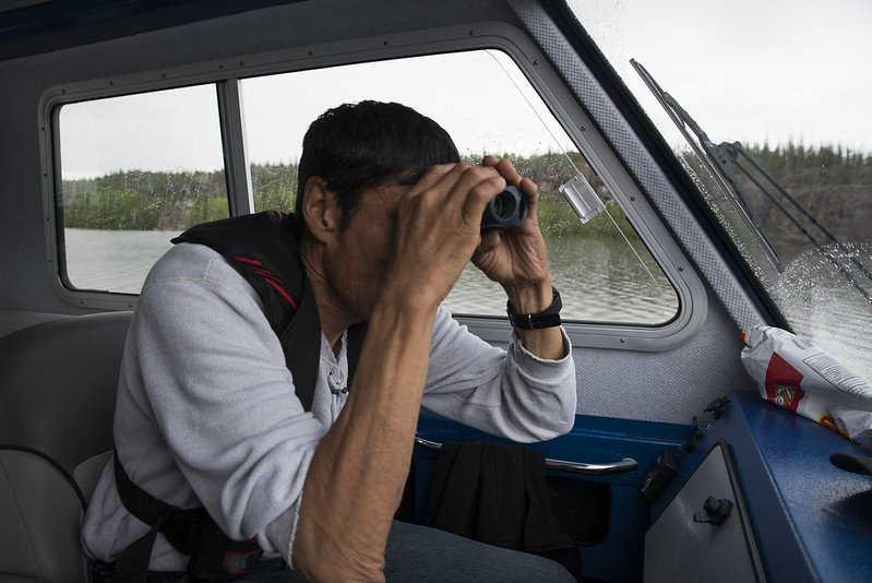 Man on boat looking through binoculars